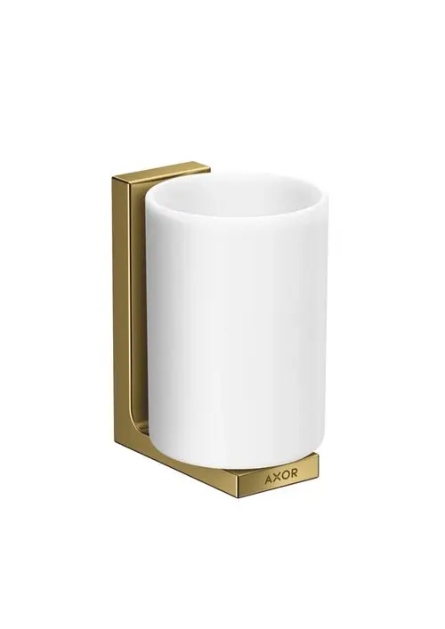 Zahnputzbecher in weiß mit Halterung in poliertem Gold, an der Wand montiert, mit dem AXOR-Logo an der Basis.